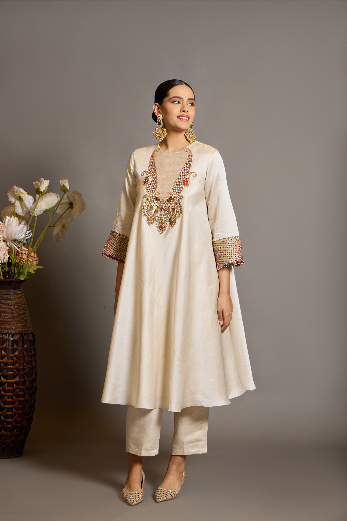 An elegant ivory kurta set crafted in a lustrous fabric, paired with tapered trousers and a fluid dupatta. Features exquisite multicolour handcrafted embroidery with ornate paisley-inspired motifs. A delicately embellished dupatta with gold edging and richly embroidered cuffs completes the look . Shop Now!