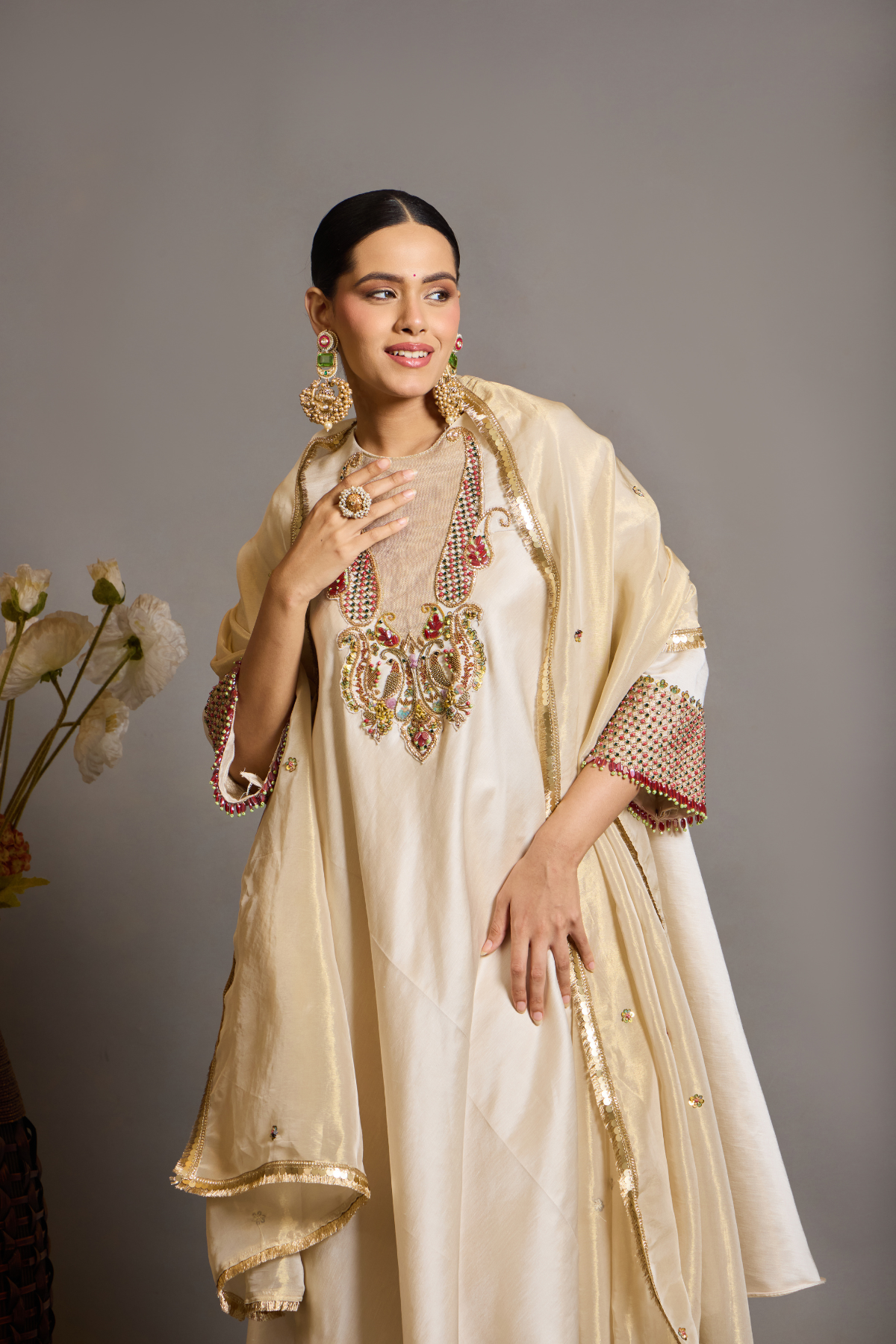An elegant ivory kurta set crafted in a lustrous fabric, paired with tapered trousers and a fluid dupatta. Features exquisite multicolour handcrafted embroidery with ornate paisley-inspired motifs. A delicately embellished dupatta with gold edging and richly embroidered cuffs completes the look . Shop Now!