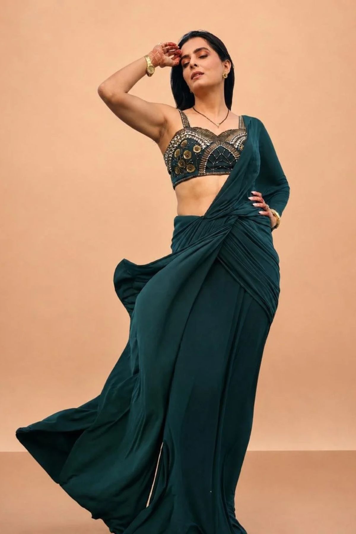 Emerald green pre-draped lycra saree with metallic rivet, sequin, bead, and cutdana work, paired with a corset blouse Shop Now!