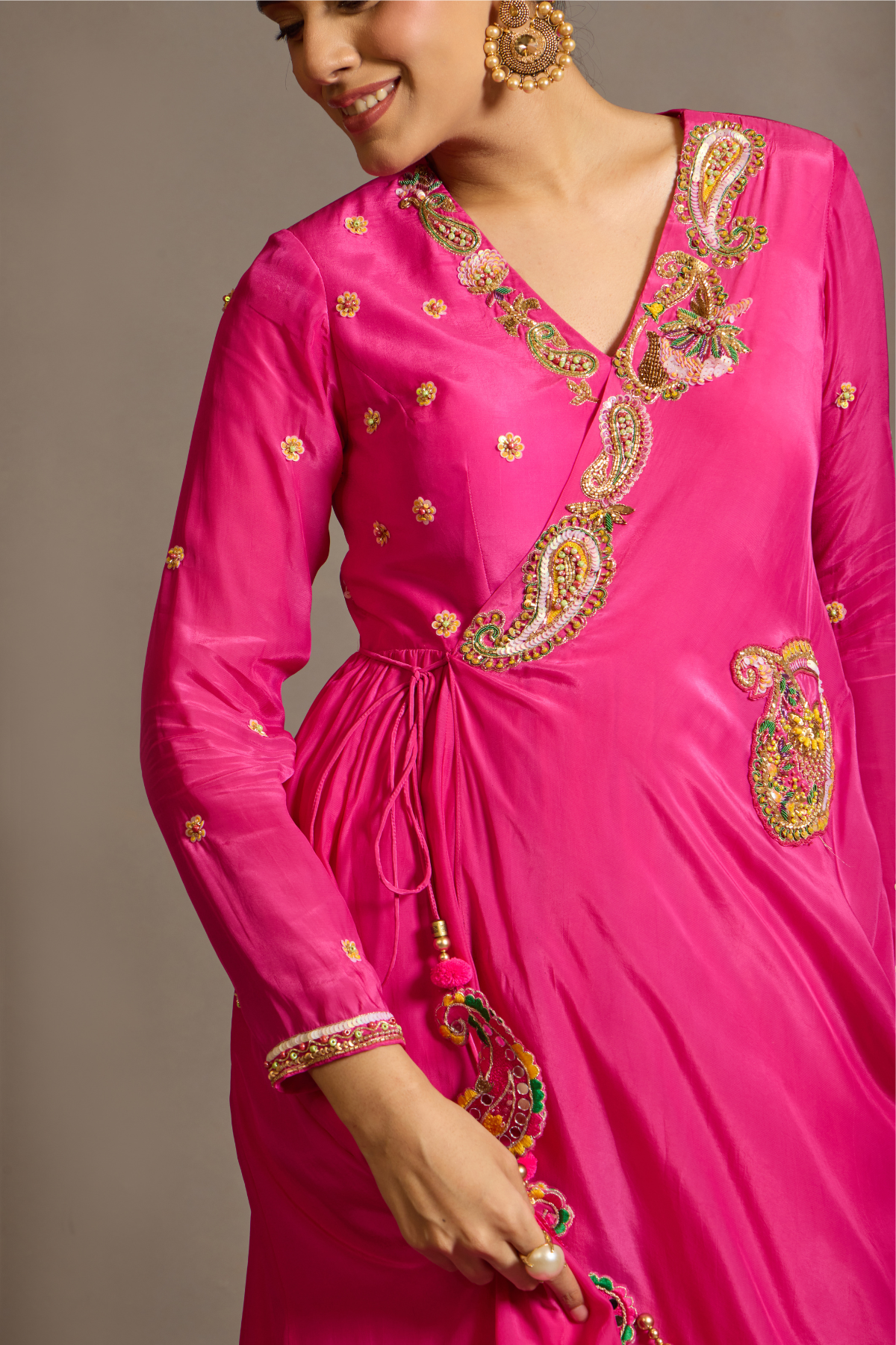 A striking fuchsia-pink Anarkali in a fluid lustrous fabric, designed with an elegant layered flare. Intricate paisley and floral embroidery in multicoloured threadwork enhances the neckline and waist. Handcrafted statement tassels adds festive charm. A vibrant contemporary Silhoutte perfect for festive soirées. Shop Now!