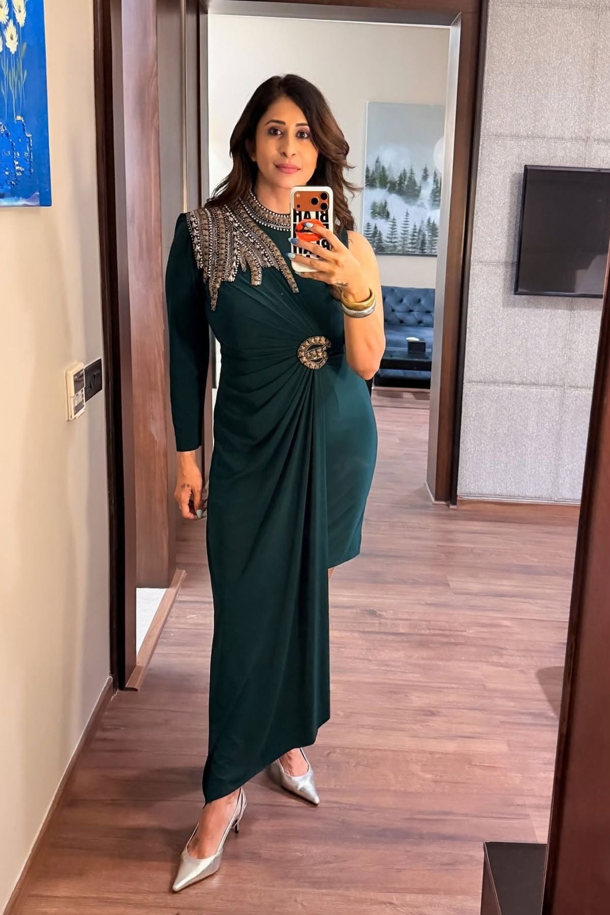 Asymmetric gown deep emerald green hue blending morder tailoring with intricate traditional embellishment fitted waist and a fluid draped faux wrap skirt at the midsection. Shop Now!