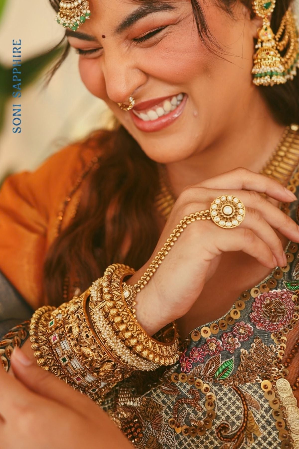 A luminous burnt-orange kurta in a rich metallic finish, elevated with an ornate handcrafted embroidered yoke. The statement neckline features intricate multicolour florals, paisleys,sequins and antique-gold detailing. Layered with a deep-navy blue metallic dupatta finished with ornate borders and delicate embellishment. A festive look that blends contemporary glamour with traditional Indian craftsmanship. Shop Now!