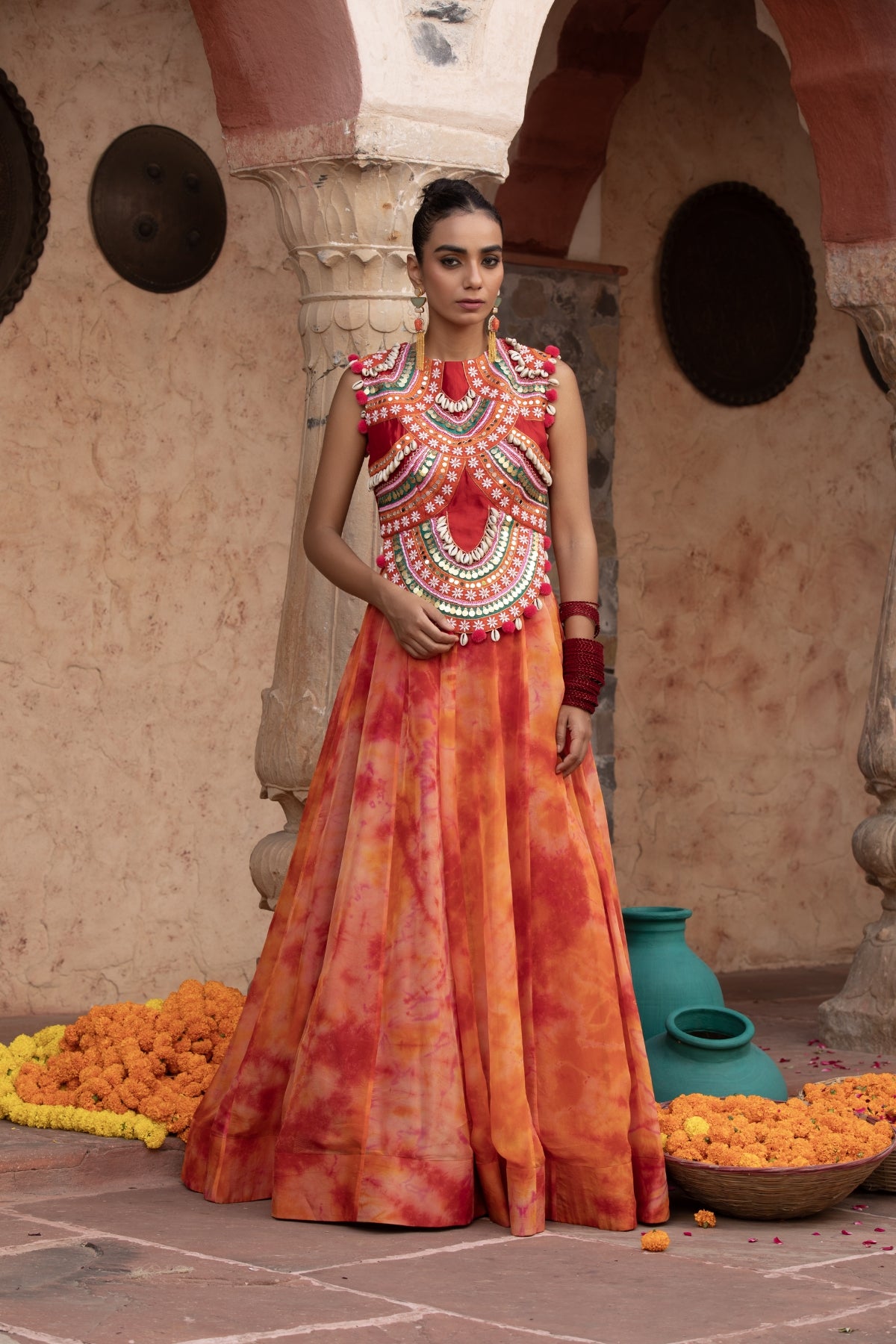 Tangerine tie-dye lehenga with coin-cadi and pearl work crop top, embellished in quirky Gujarati style with pom-pom and puppet tassels Shop Now!