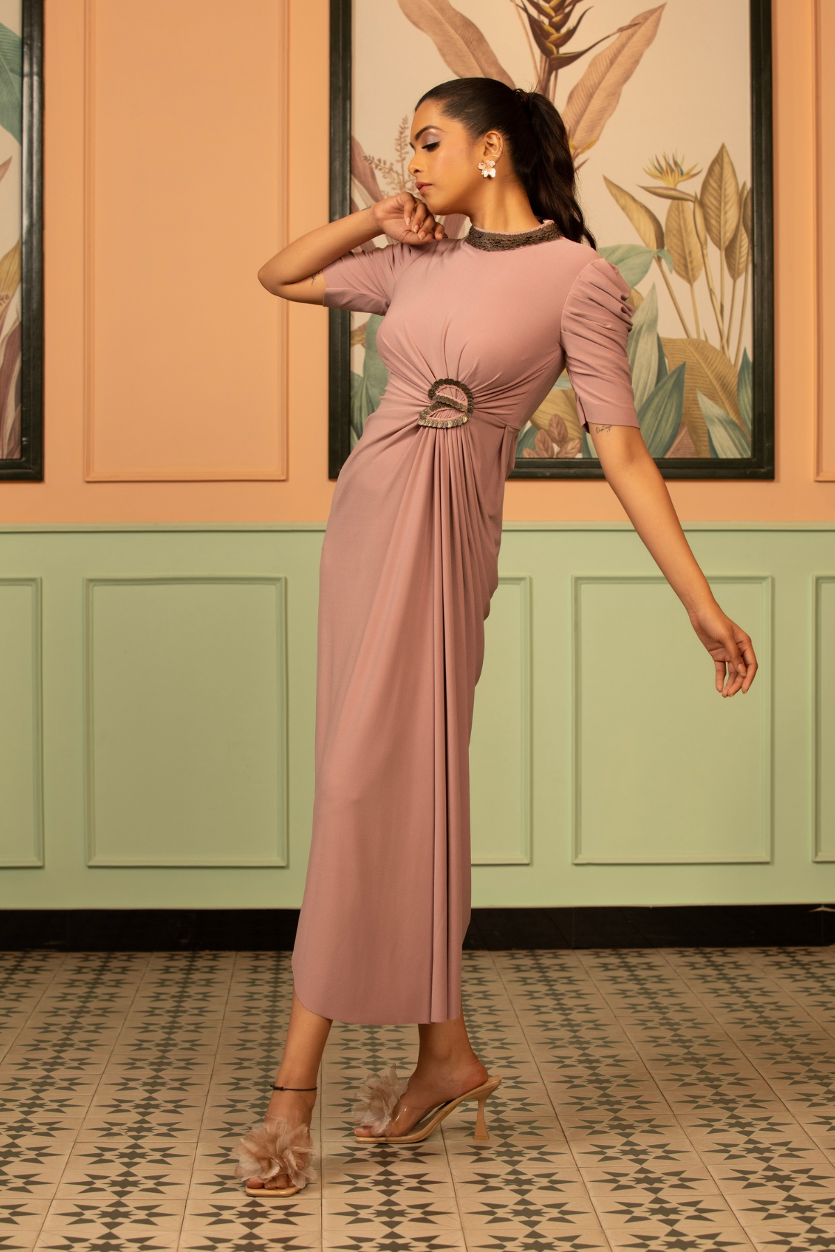 The blush coin drape dress fitted bodices with distinctive drape wrape style front that gather at the waist puff sleeve a classic high round neckline hand work elements like pearl beads Shop Now!