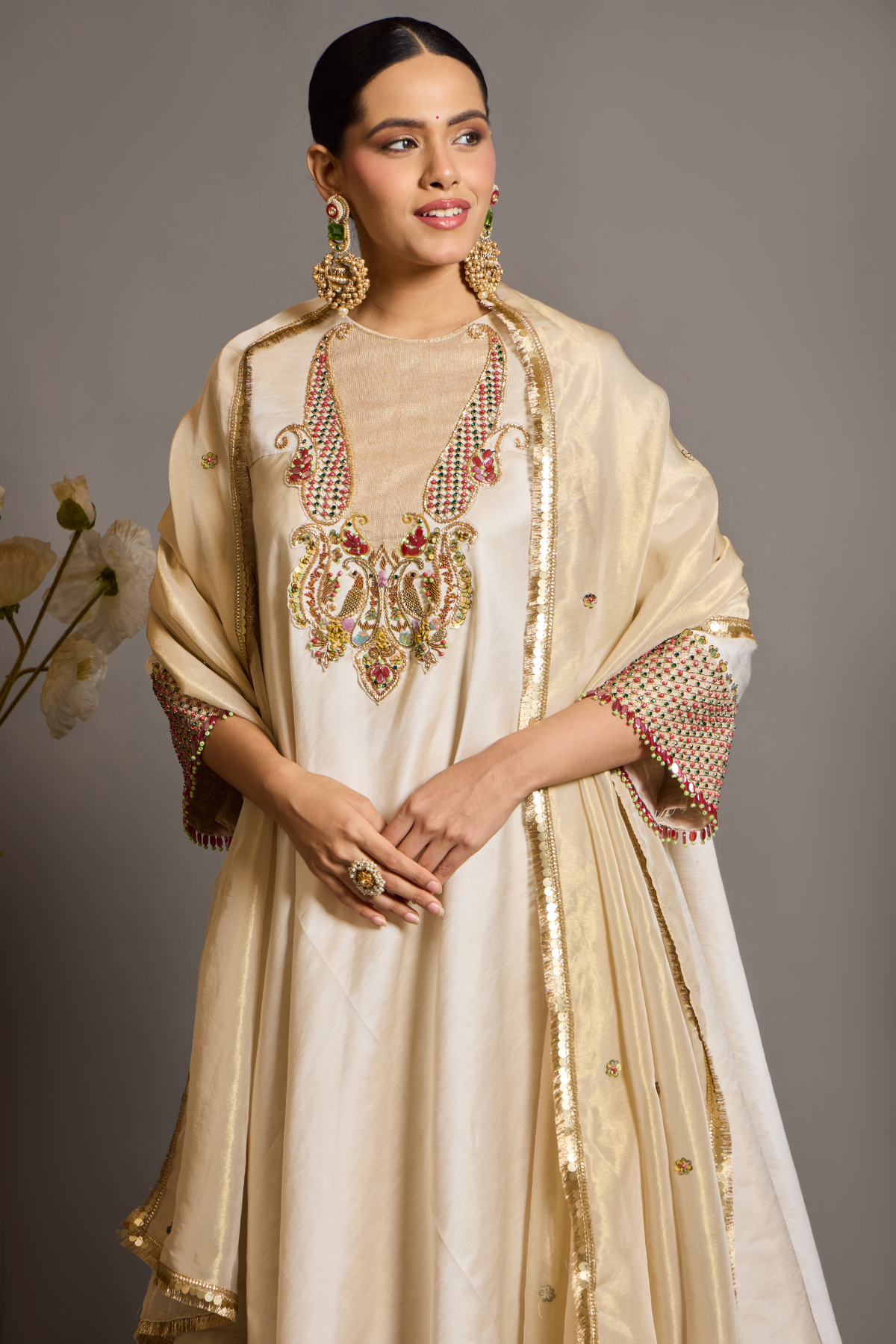 An elegant ivory kurta set crafted in a lustrous fabric, paired with tapered trousers and a fluid dupatta. Features exquisite multicolour handcrafted embroidery with ornate paisley-inspired motifs. A delicately embellished dupatta with gold edging and richly embroidered cuffs completes the look . Shop Now!