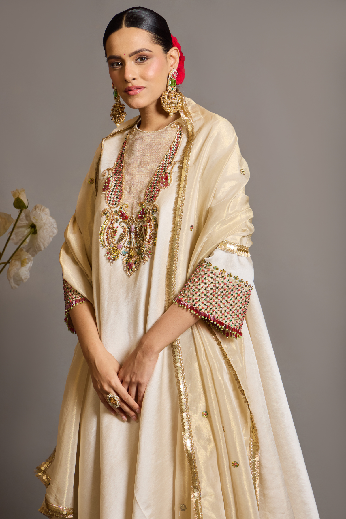 An elegant ivory kurta set crafted in a lustrous fabric, paired with tapered trousers and a fluid dupatta. Features exquisite multicolour handcrafted embroidery with ornate paisley-inspired motifs. A delicately embellished dupatta with gold edging and richly embroidered cuffs completes the look . Shop Now!
