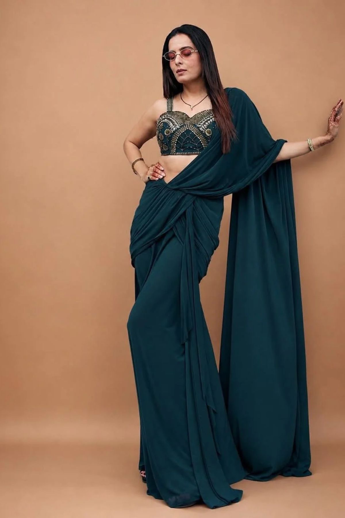 Emerald green pre-draped lycra saree with metallic rivet, sequin, bead, and cutdana work, paired with a corset blouse Shop Now!