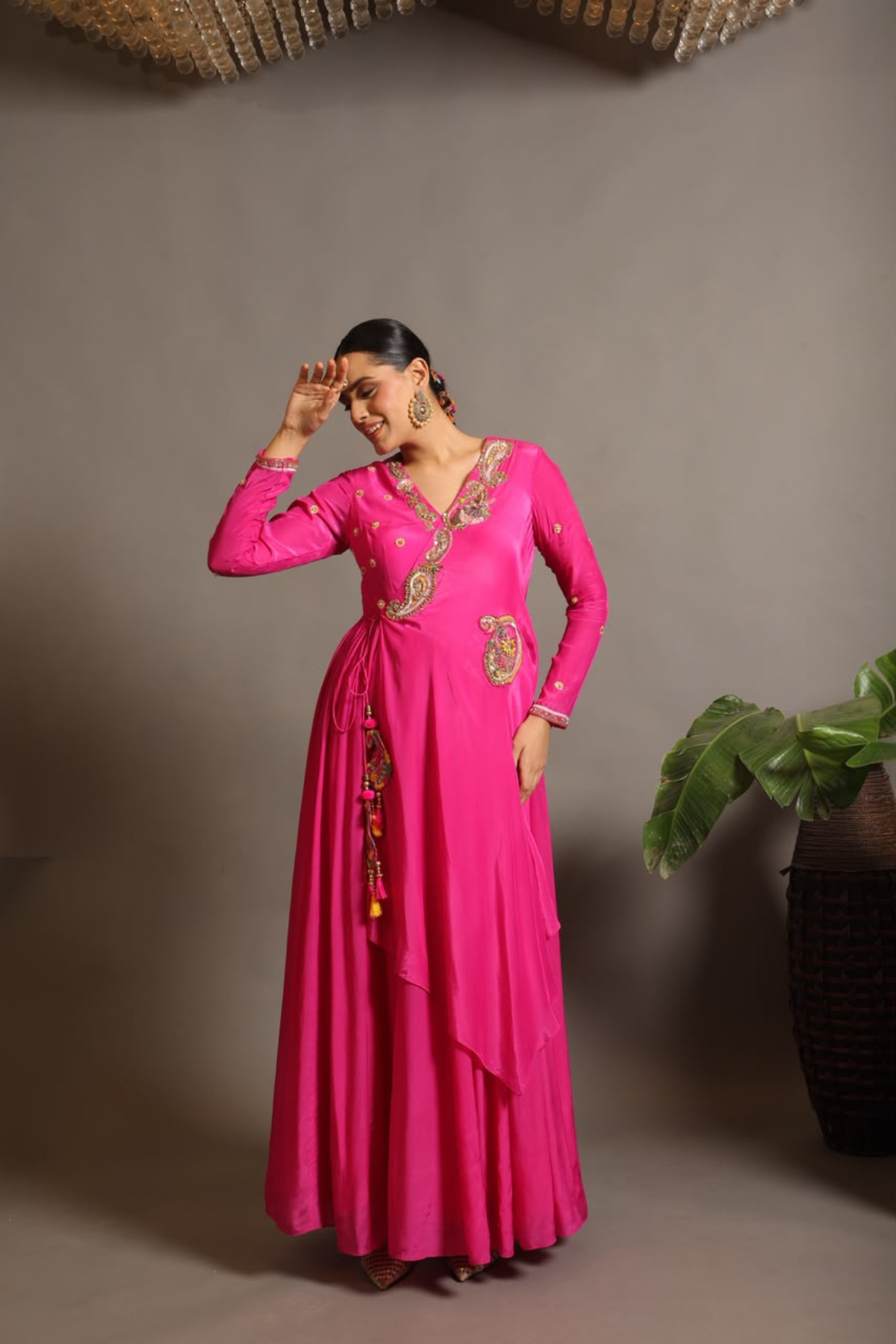 A striking fuchsia-pink Anarkali in a fluid lustrous fabric, designed with an elegant layered flare. Intricate paisley and floral embroidery in multicoloured threadwork enhances the neckline and waist. Handcrafted statement tassels adds festive charm. A vibrant contemporary Silhoutte perfect for festive soirées. Shop Now!