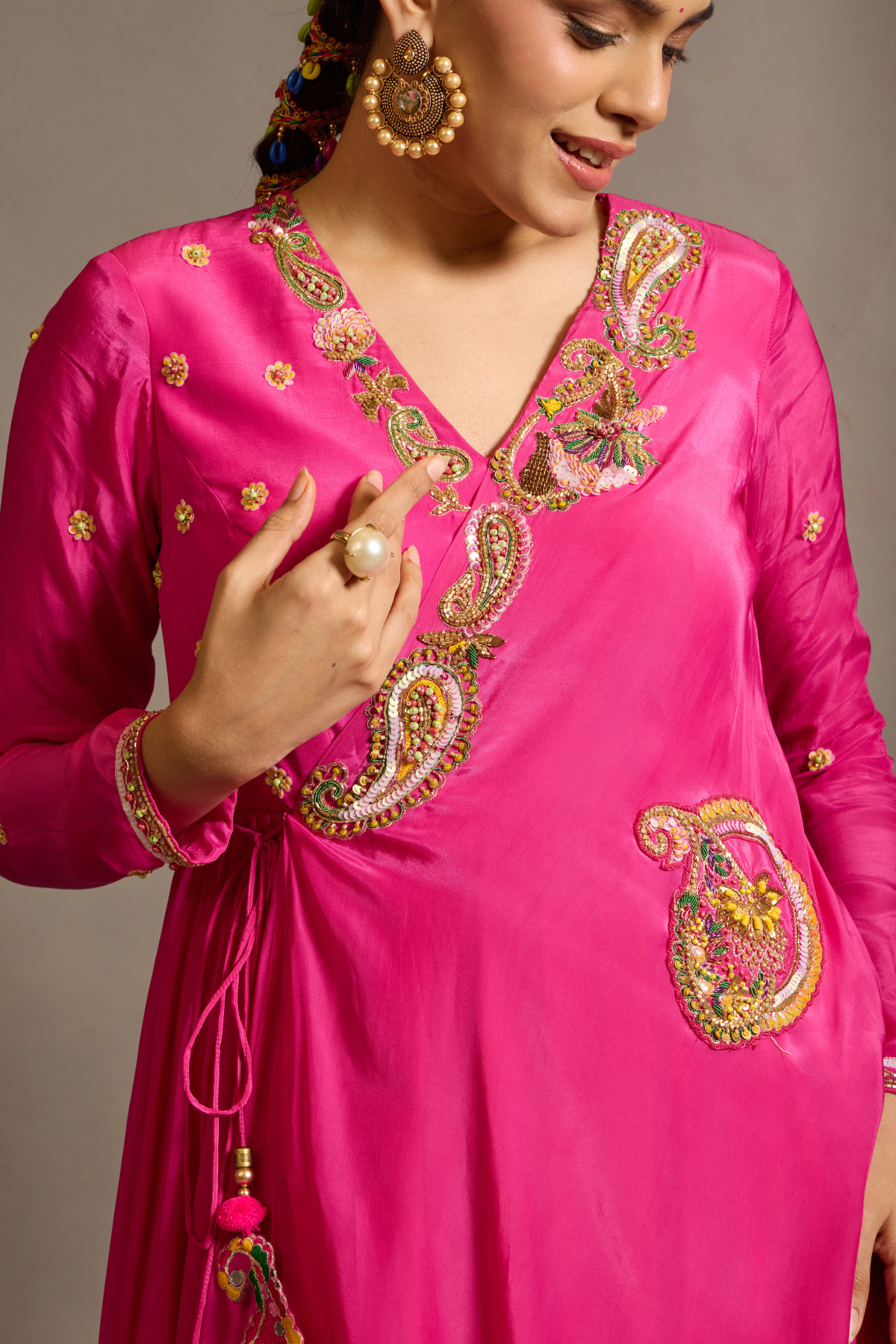 A striking fuchsia-pink Anarkali in a fluid lustrous fabric, designed with an elegant layered flare. Intricate paisley and floral embroidery in multicoloured threadwork enhances the neckline and waist. Handcrafted statement tassels adds festive charm. A vibrant contemporary Silhoutte perfect for festive soirées. Shop Now!