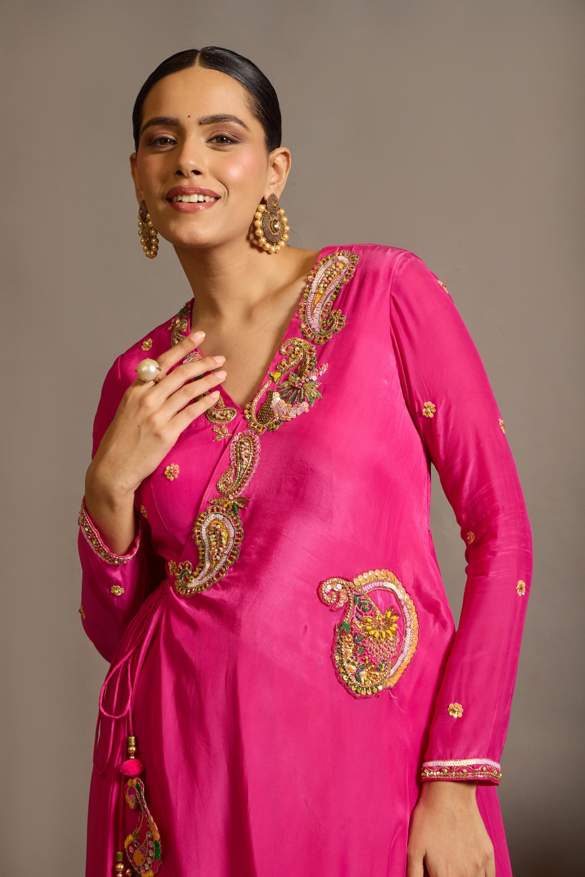 A striking fuchsia-pink Anarkali in a fluid lustrous fabric, designed with an elegant layered flare. Intricate paisley and floral embroidery in multicoloured threadwork enhances the neckline and waist. Handcrafted statement tassels adds festive charm. A vibrant contemporary Silhoutte perfect for festive soirées. Shop Now!