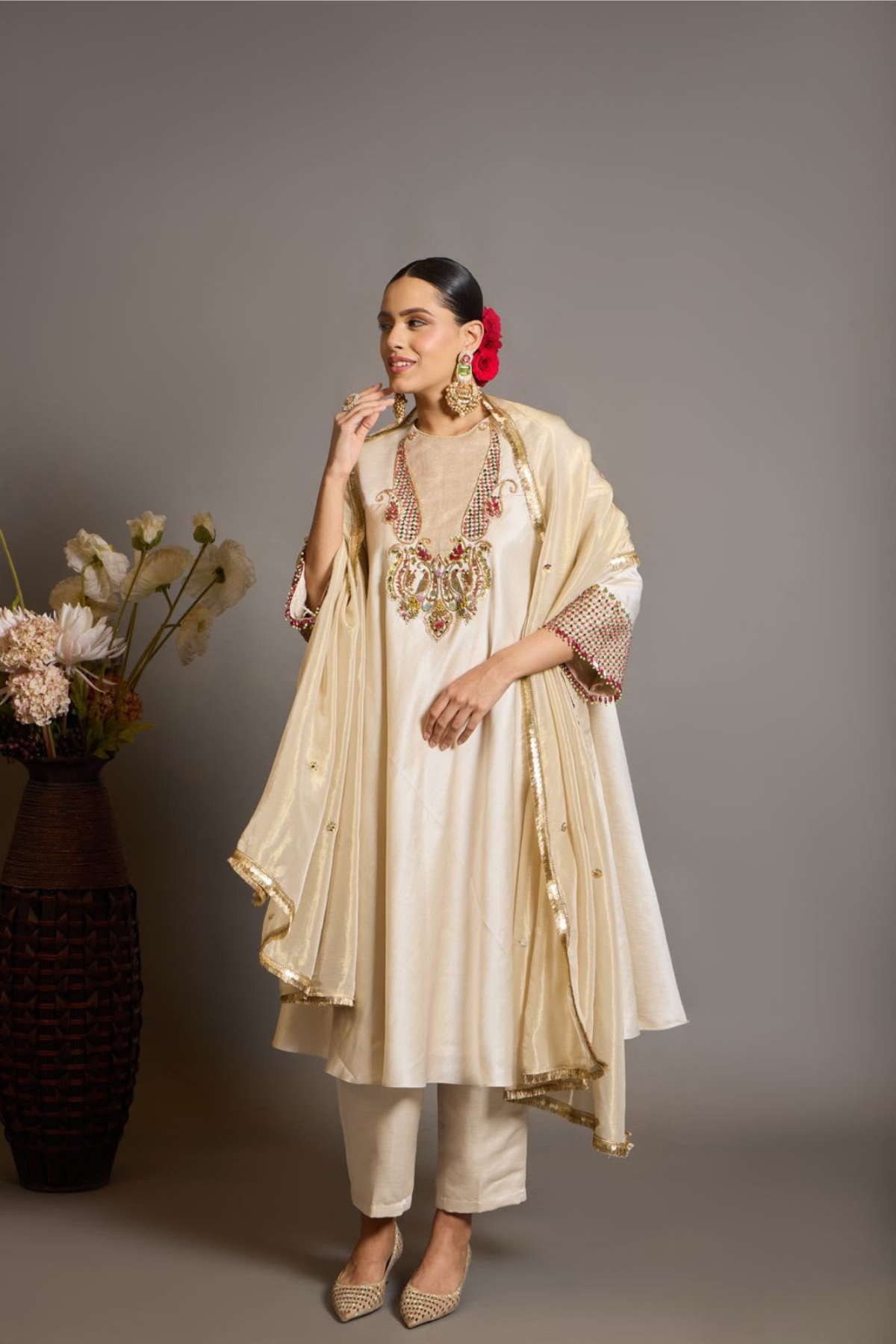 An elegant ivory kurta set crafted in a lustrous fabric, paired with tapered trousers and a fluid dupatta. Features exquisite multicolour handcrafted embroidery with ornate paisley-inspired motifs. A delicately embellished dupatta with gold edging and richly embroidered cuffs completes the look .Shop Now!