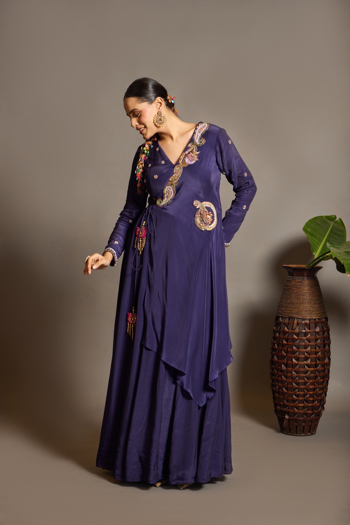 A sophisticated festive deep purple Anarkali crafted in luxurious fluid fabric with a graceful layered flare. Intricate multicolour floral and paisley embroidered adds a rich artisanal touch.handcrafted statement tassels ,a flattering tie-up waist & delicate embellishment.  Shop Now!