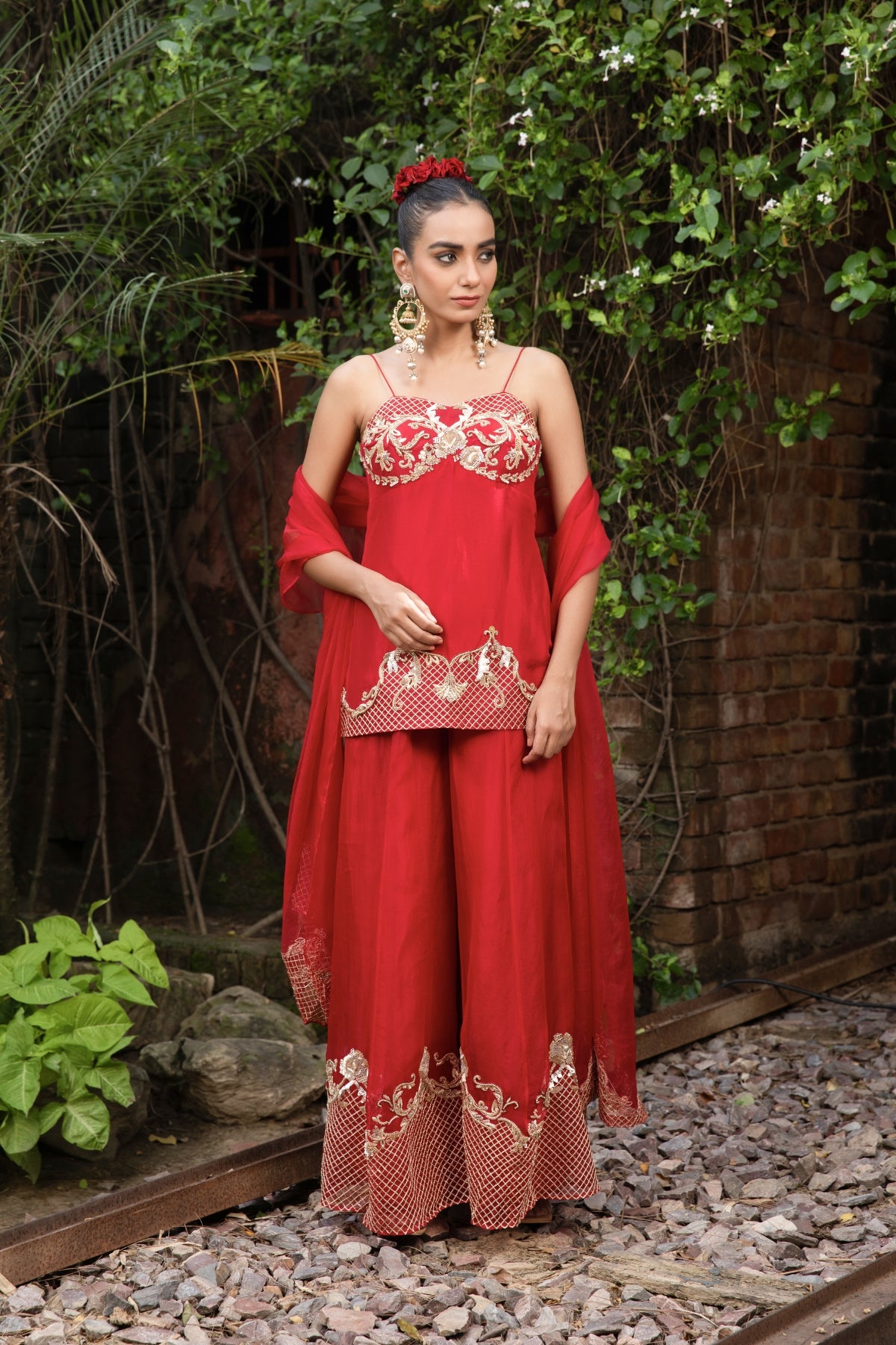 Scarlet red silk corset peplum top with Rococo-inspired hand embellishments, paired with organza palazzo and dupatta featuring zari. Shop Now!