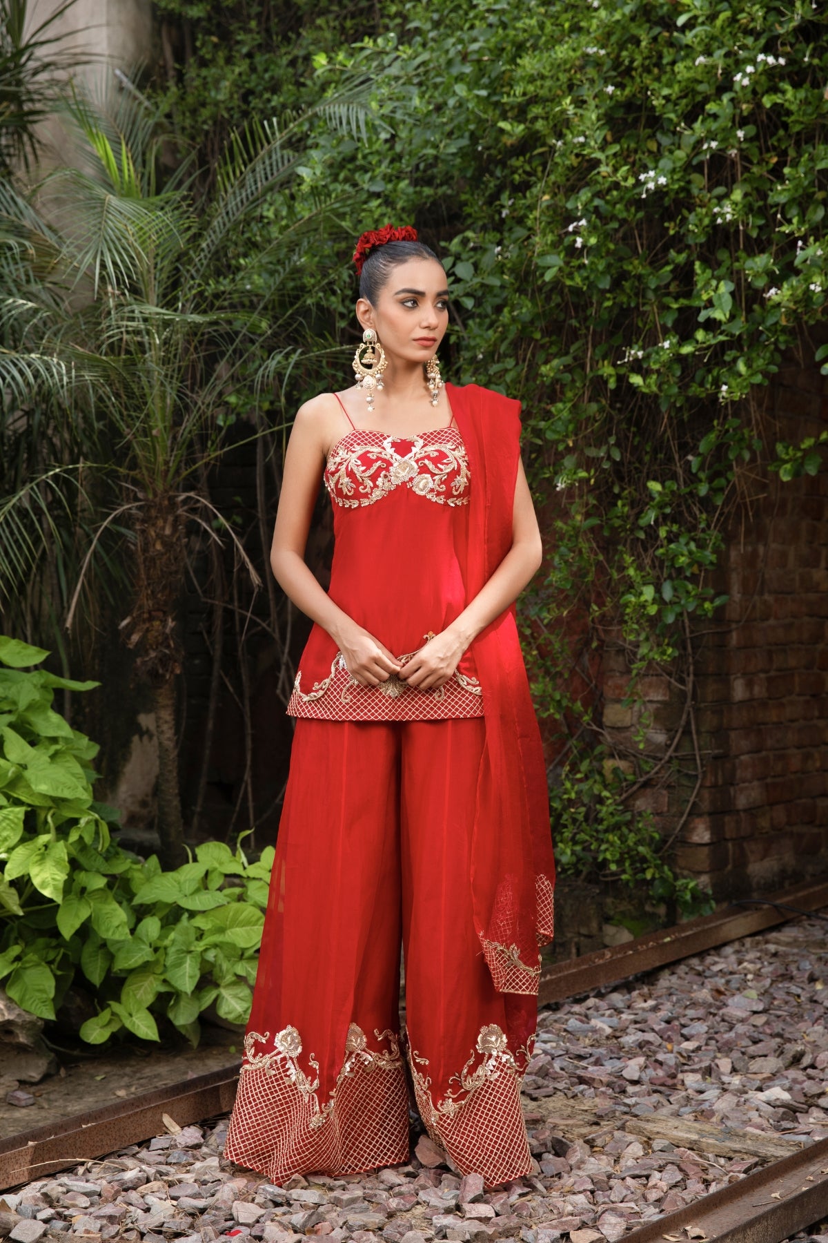 Scarlet red silk corset peplum top with Rococo-inspired hand embellishments, paired with organza palazzo and dupatta featuring zari. Shop Now!