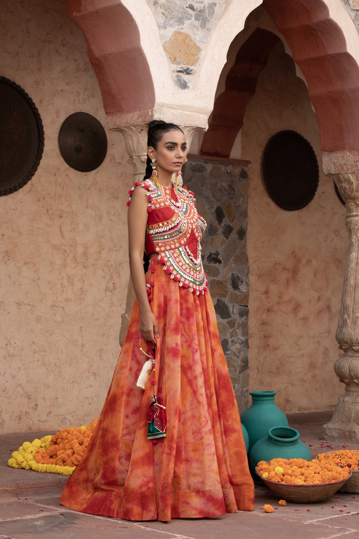 Tangerine tie-dye lehenga with coin-cadi and pearl work crop top, embellished in quirky Gujarati style with pom-pom and puppet tassels Shop Now!
