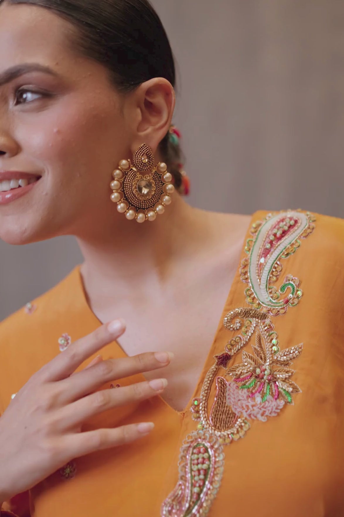 A vibrant marigold-orange Anarkali crafted in a fluid, lustrous fabric with a graceful layered silhouette. Adorned with intricate multicolour paisley embroidery and delicate scattered embellishments. Features a flattering tie-up waist with handcrafted tassels and elegant embroidered work. Shop Now!